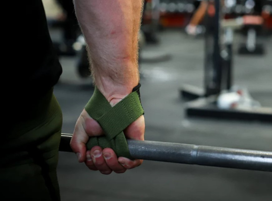 Close-up of a man's hand, using lifting straps with a barbell