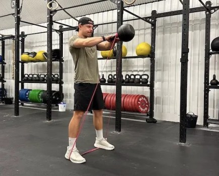 Man in a gym performing a kettlebell swing
