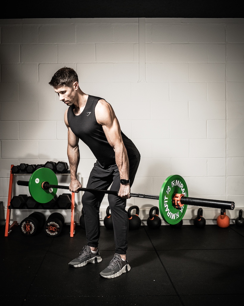 PT demonstrating how to do a barbell power clean as part of a metabolic resistance training workout