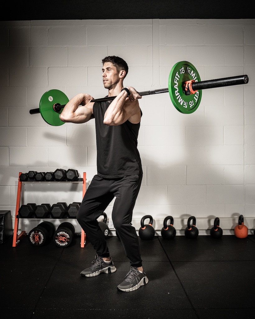 PT demonstrating how to do a barbell front squat as part of a metabolic resistance training workout