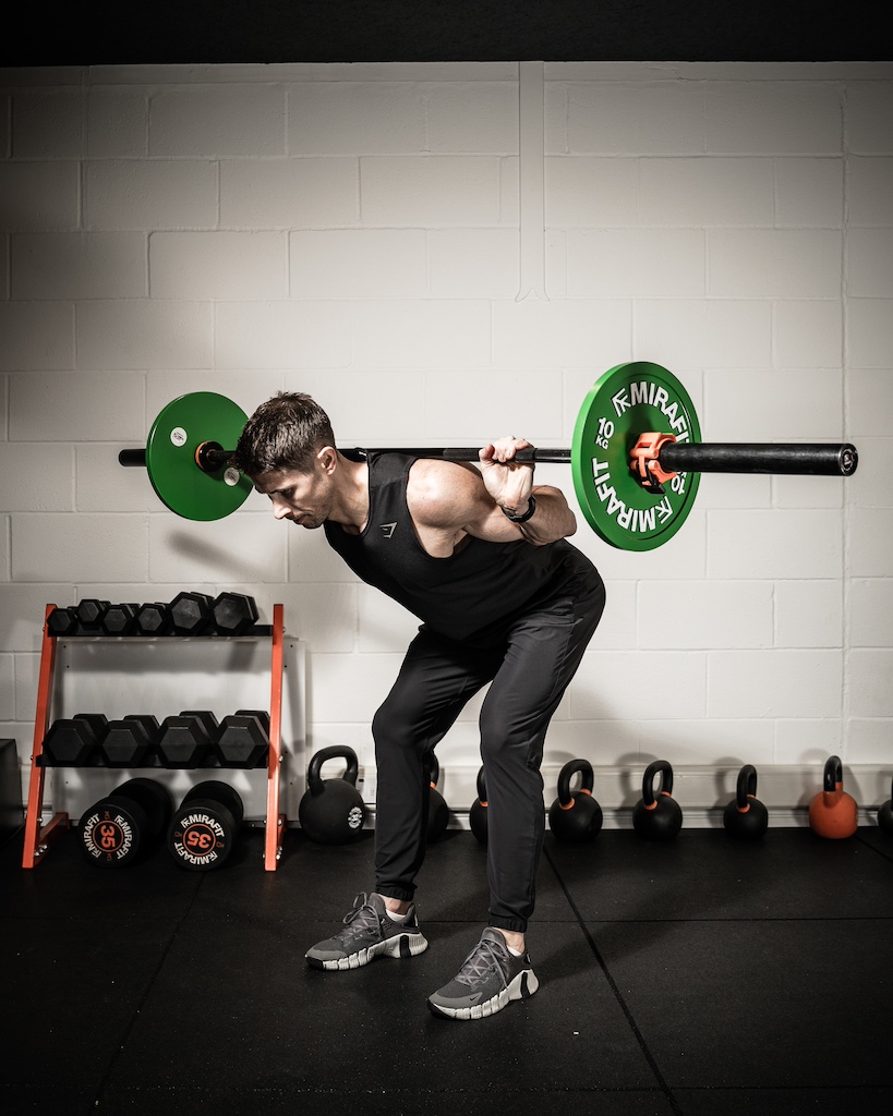 PT demonstrating how to do a barbell good morning as part of an MRT workout