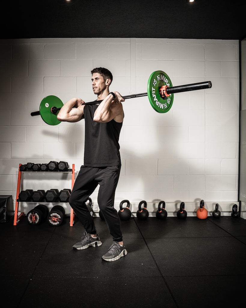 PT demonstrating how to do a barbell push press as part of an MRT workout