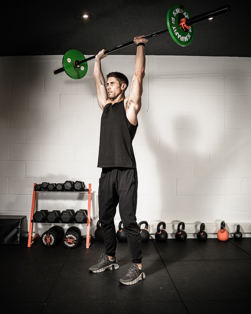 PT demonstrating how to do a barbell push press as part of an MRT workout