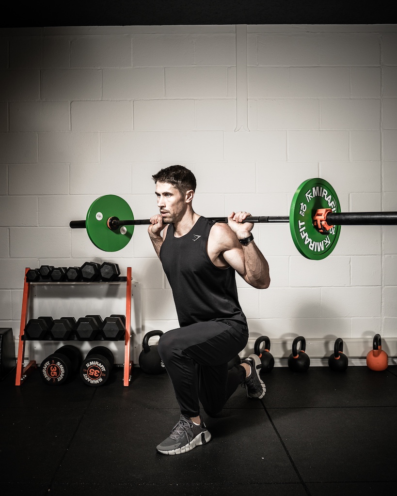 PT demonstrating how to do a barbell reverse lunge as part of an MRT workout