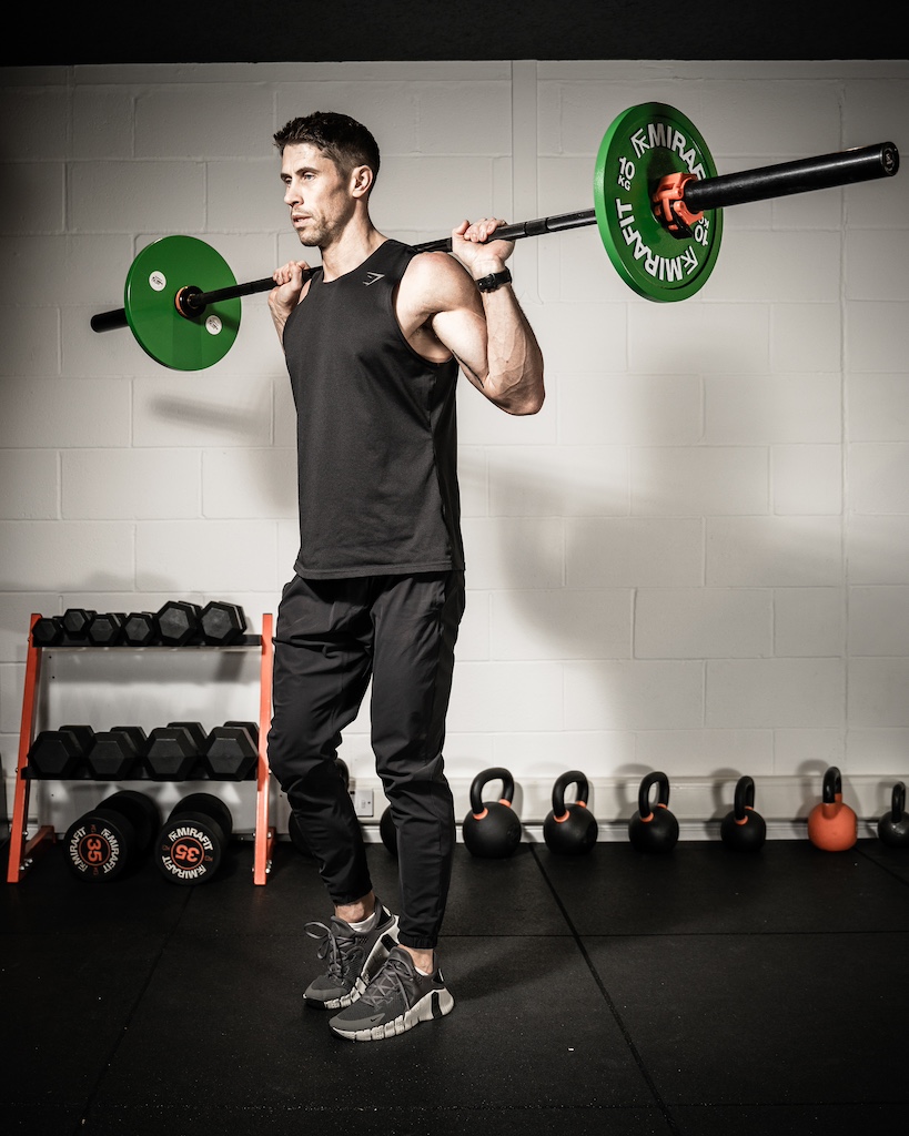 PT demonstrating how to do a barbell reverse lunge as part of an MRT workout