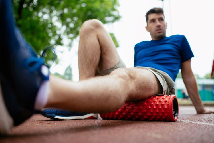 Close-up of a man massaging his hamstrings with a foam roller