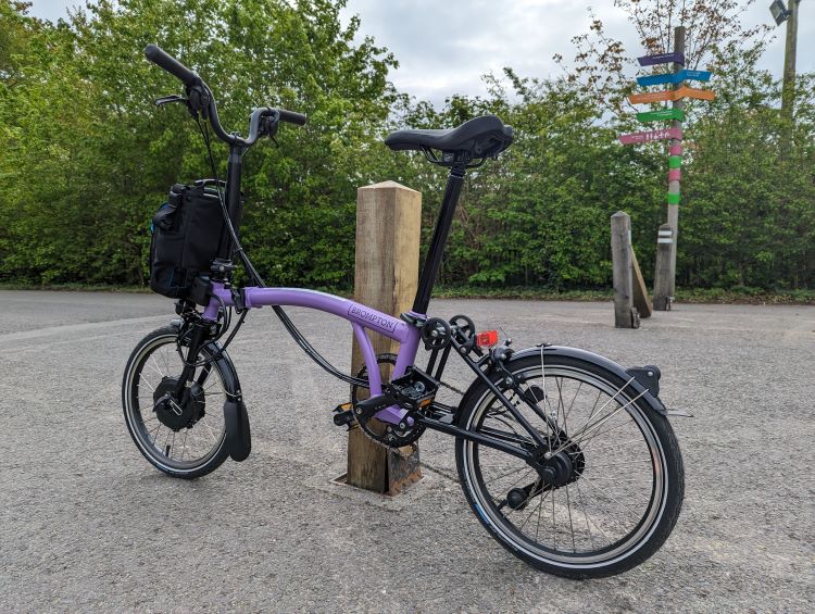 A Brompton bike leaning against a post