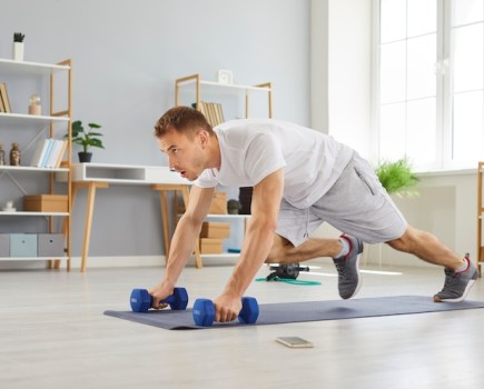 A man exercising with dumbbells at home