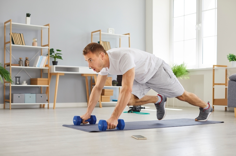 A man exercising with dumbbells at home