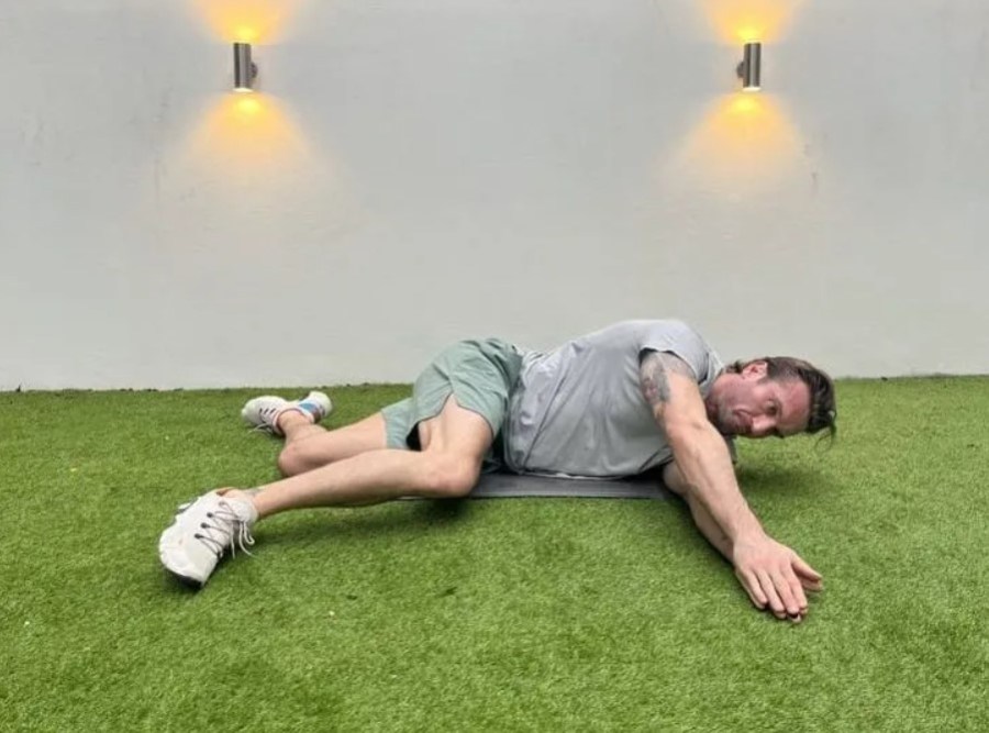 Man performing a side-lying windmill stretch