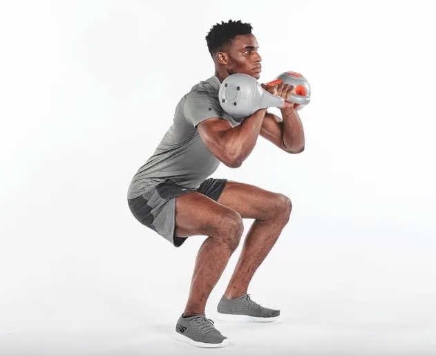 Man squatting and exercising with kettlebells