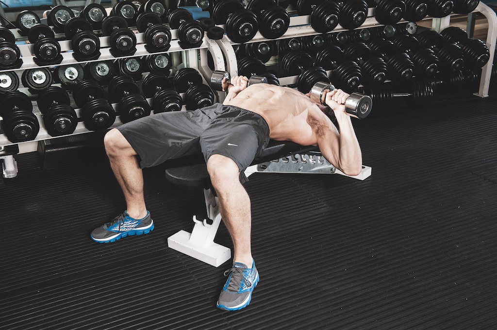 man performing dumbbell bench press in the gym