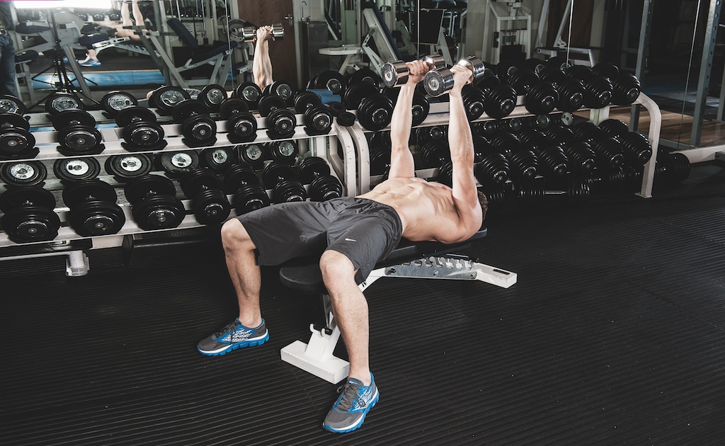 man doing dumbbell flyes in the gym