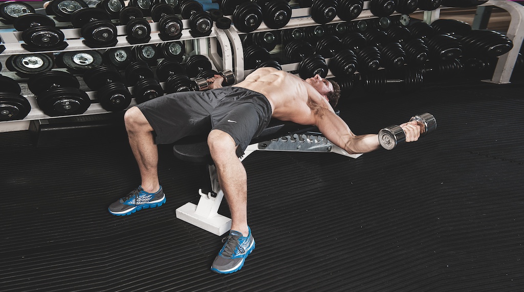 man doing dumbbell flyes in the gym