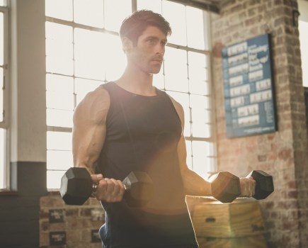 Serious man lifting dumbbells at the gym