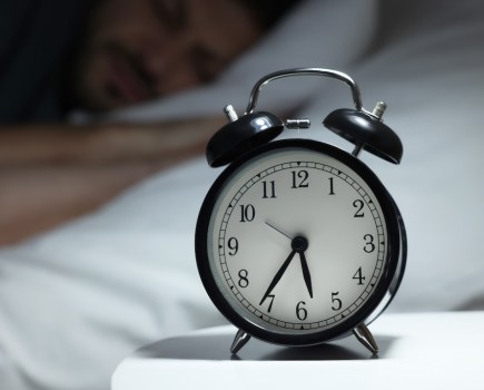 Man sleeping in bed, focus on alarm clock