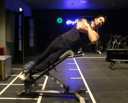 Man performing a 45 degree side bend exercise on a weight bench