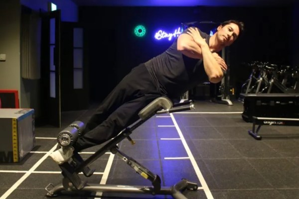 Man performing a 45 degree side bend exercise on a weight bench