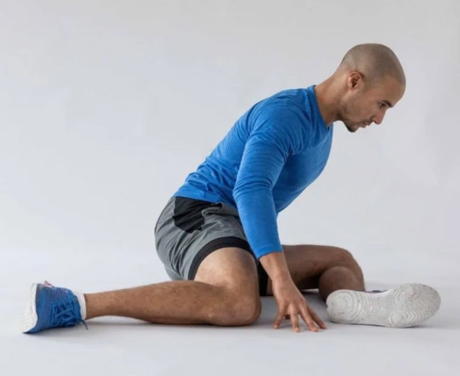 A man performing leg stretches on the floor