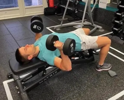 Man doing dumbbell chest presses on an exercise bench