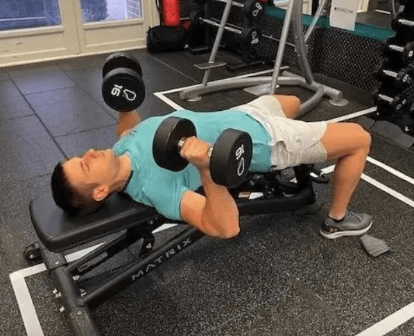 Man doing dumbbell chest presses on an exercise bench