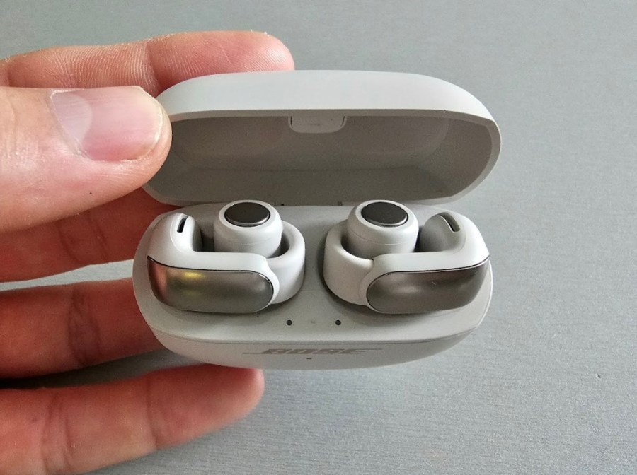 Hand holding a case with open-ear earbuds