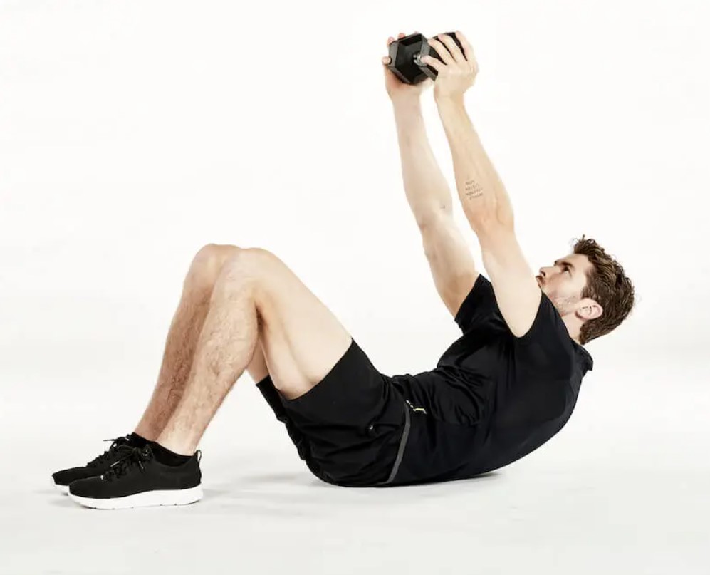 Man performing a dumbbell crunch reach exercise