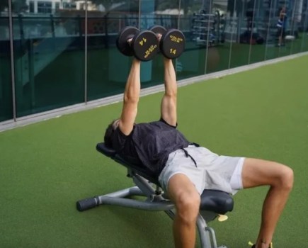 Man performing dumbbell exercises on a workout bench