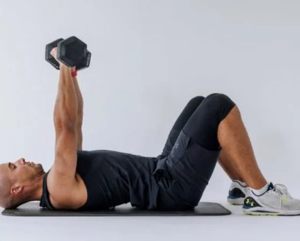 Man performing a floor chest press on an exercise mat