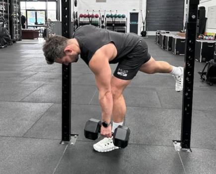 personal trainer doing single-leg RDL in a gym