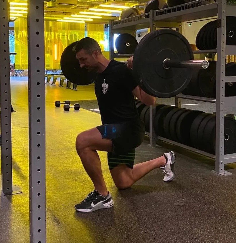 Man in a gym performing a reverse lunge