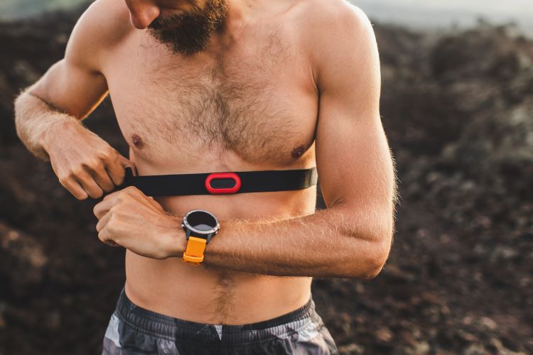 Bare-chested man strapping on a heart rate monitor