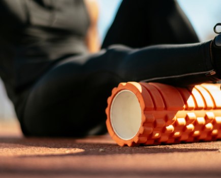 Close-up of a man massaging his calf with a foam roller