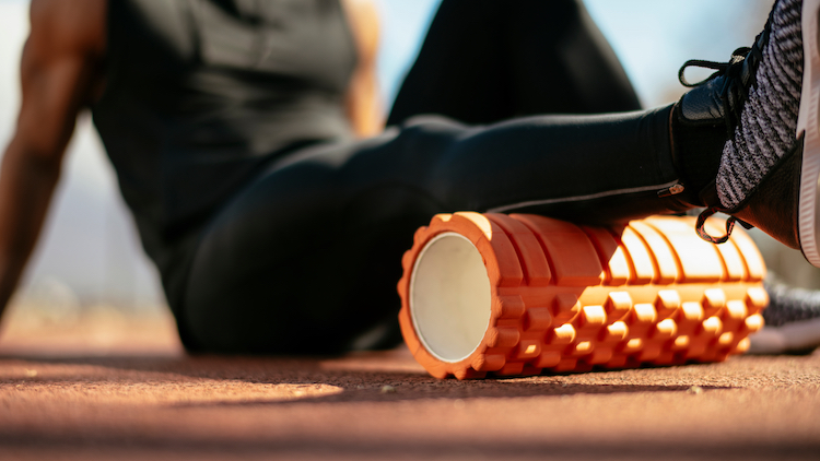 Close-up of a man massaging his calf with a foam roller