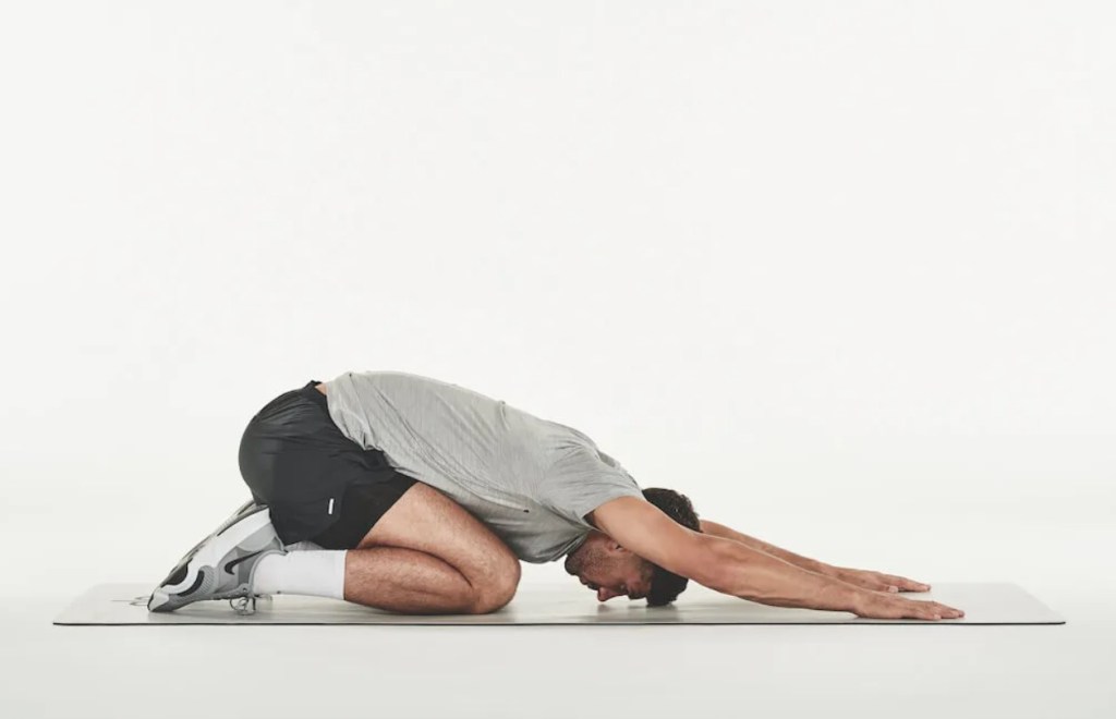 Man performing a child's pose on an exercise mat