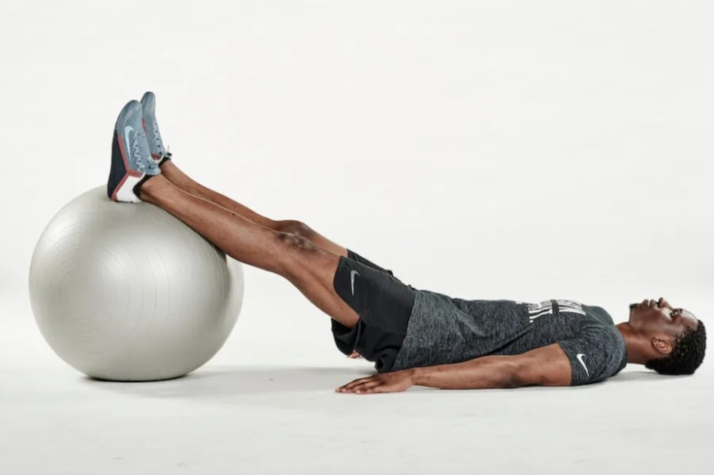 Man performing an exercise ball glute bridge