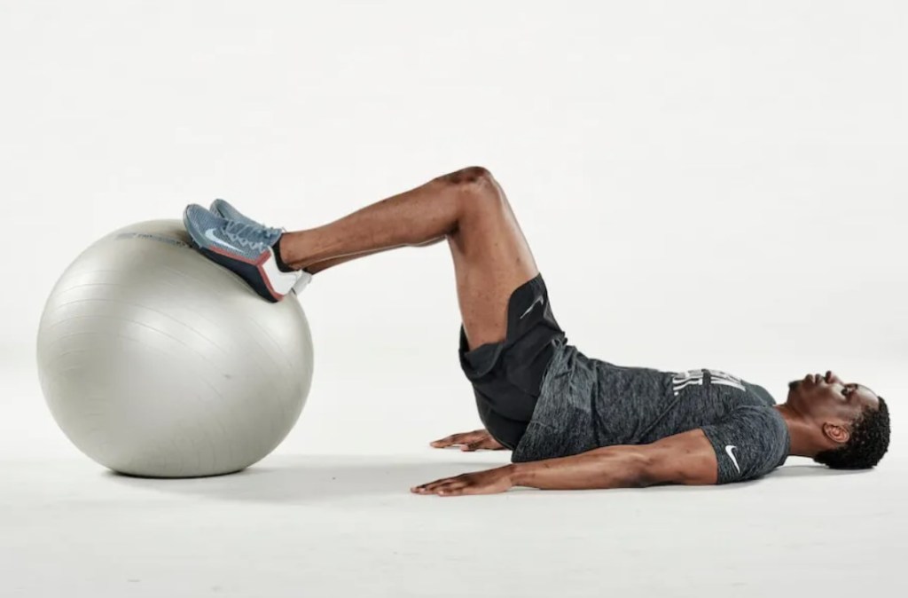 Man performing an exercise ball hamstring curl