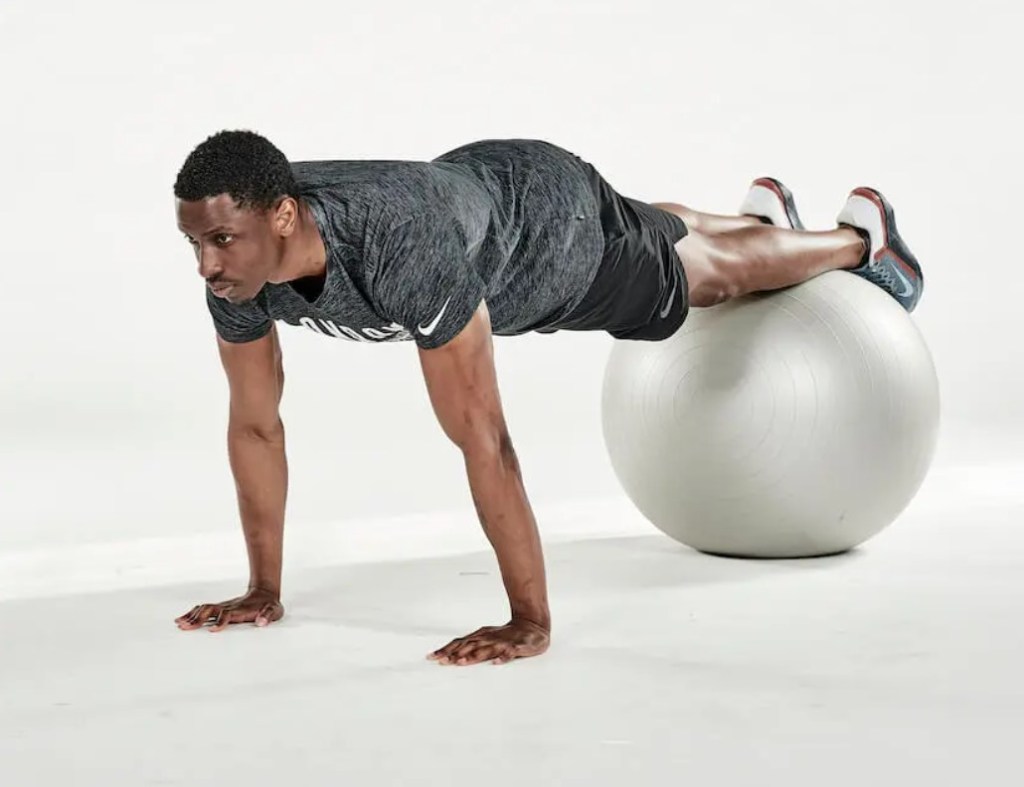 Man performing an exercise ball jack-knife