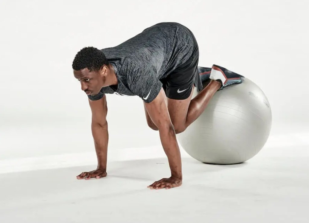 Man performing an exercise ball jack-knife