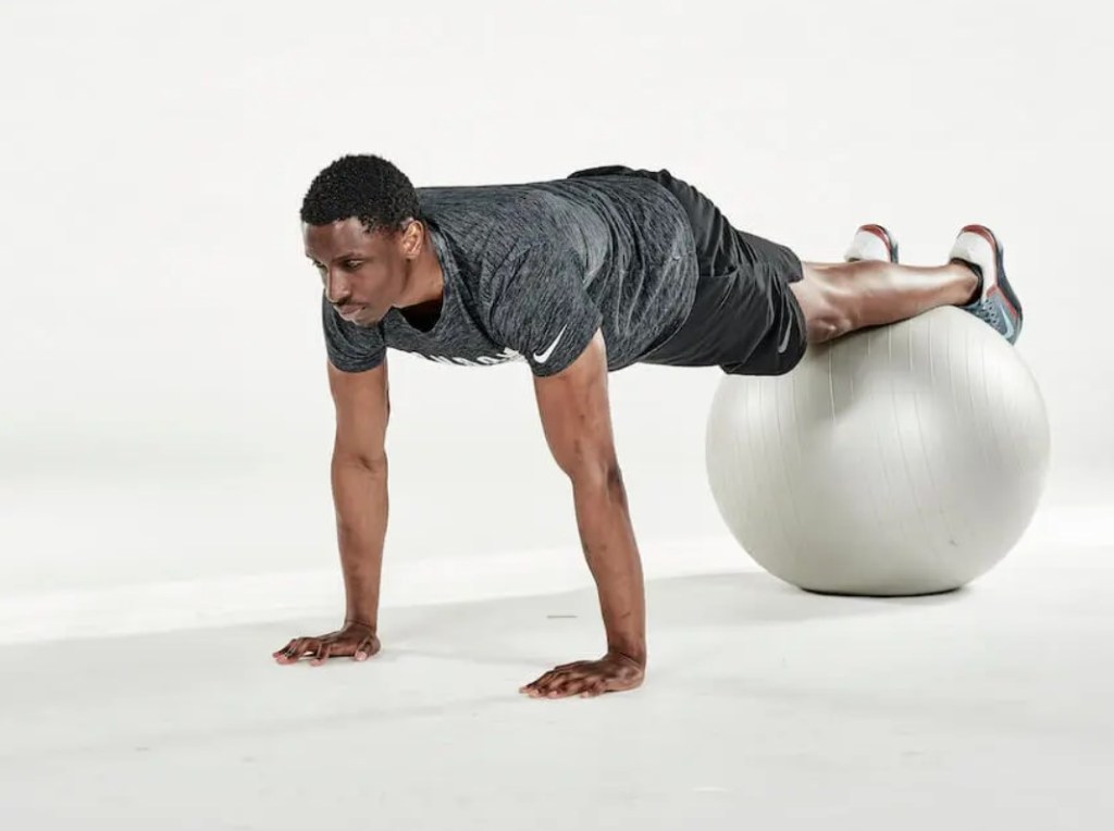 Man performing an exercise ball jack-knife twist