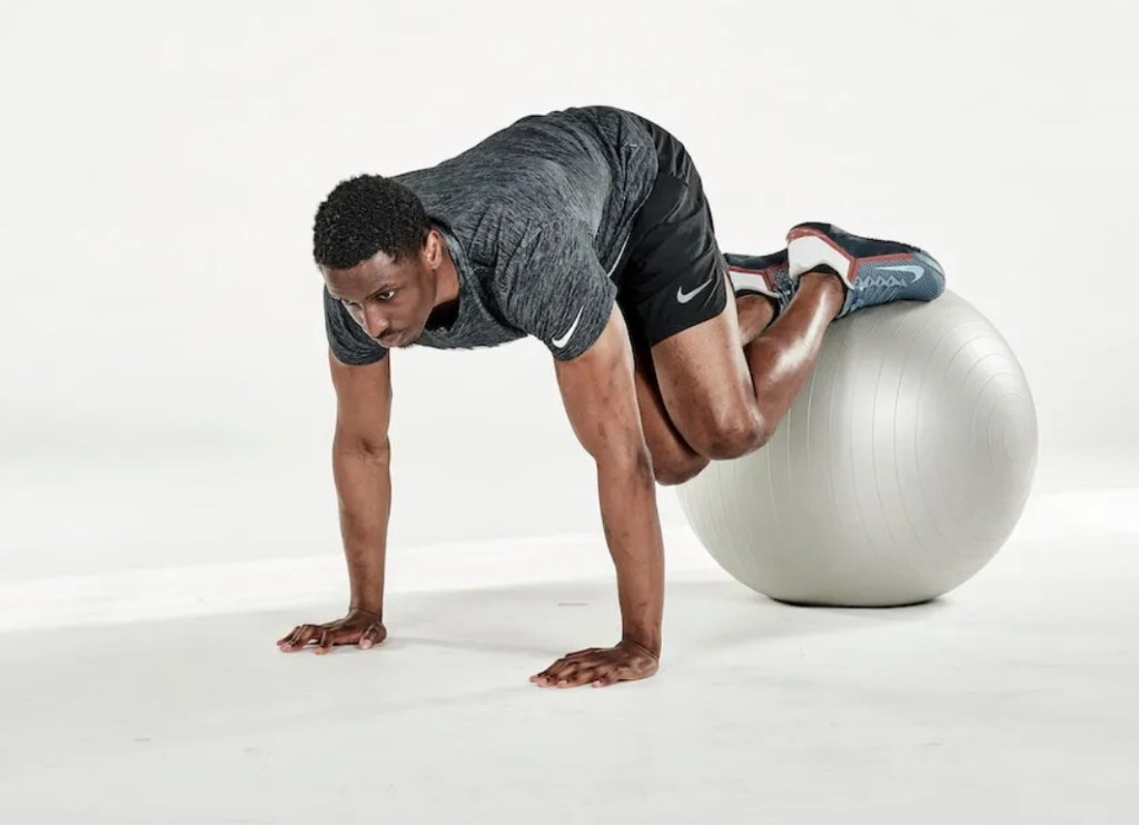 Man performing an exercise ball jack-knife twist