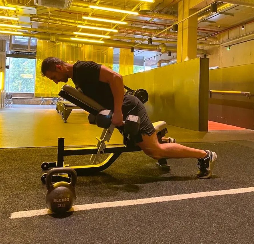 Man in a gym performing an incline dumbbell row