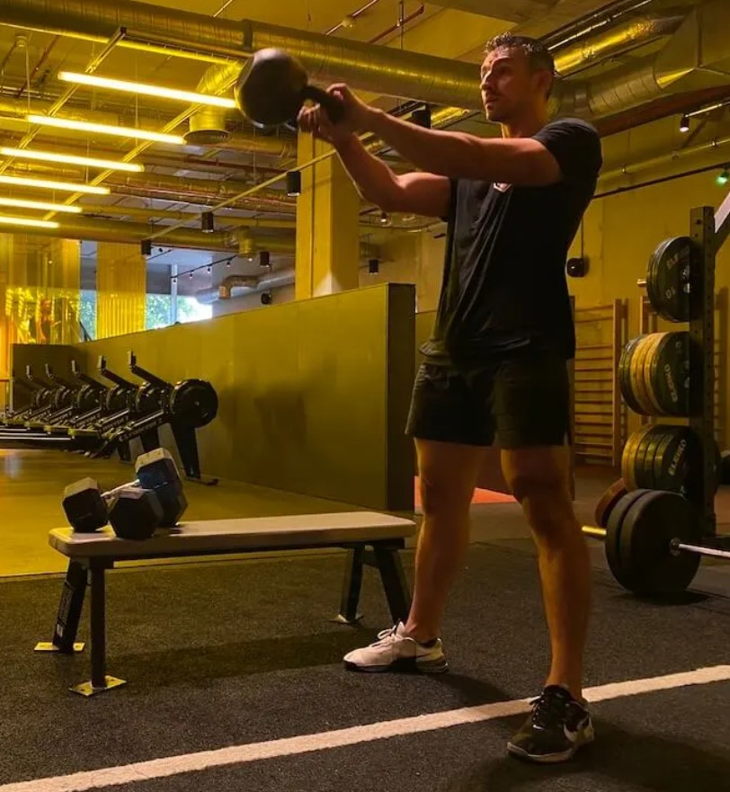 Man in a gym performing a kettlebell swing