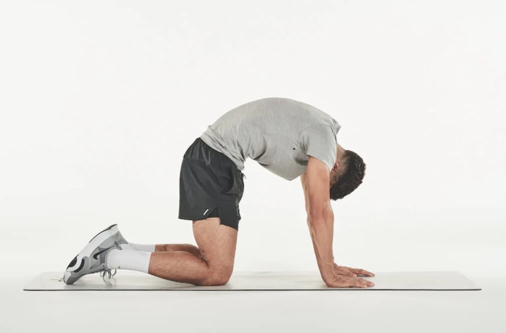 Man performing a cat cow yoga pose