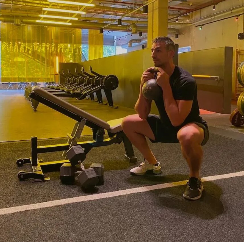 Man in a gym performing a kettlebell goblet squat