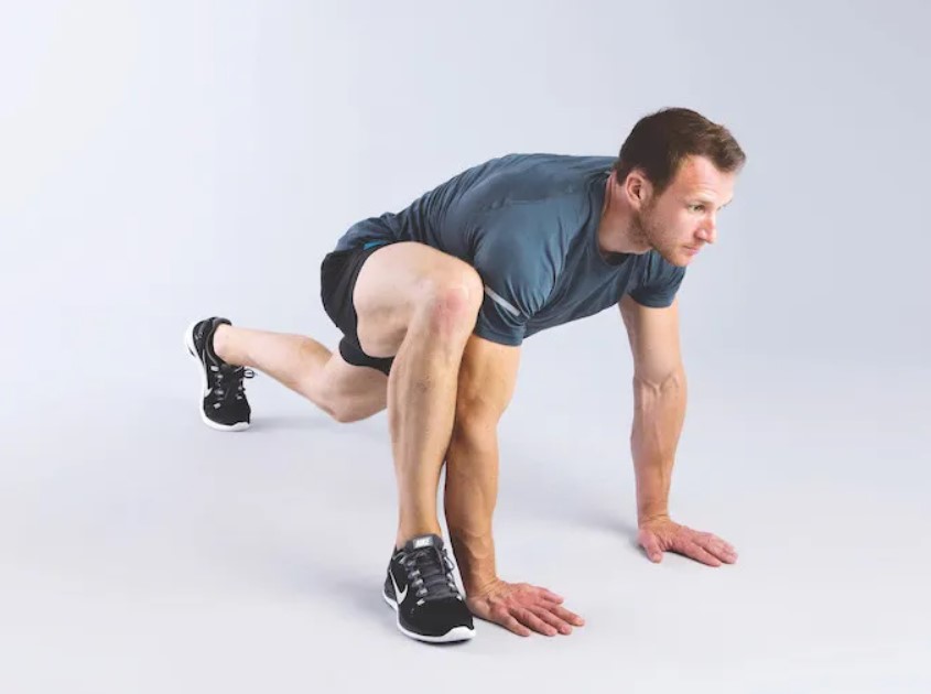 Man performing a wide mountain climber stretch