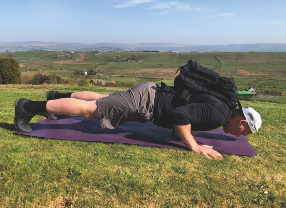 Man performing a push-up with a backpack