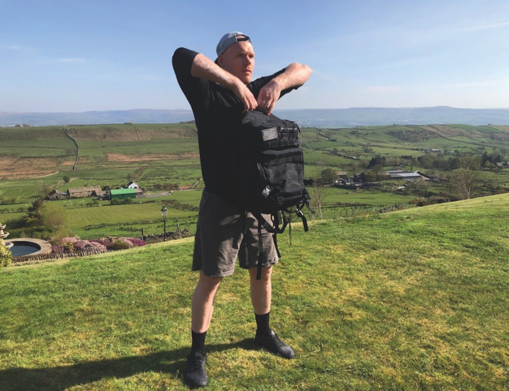 Man performing an upright row with a backpack