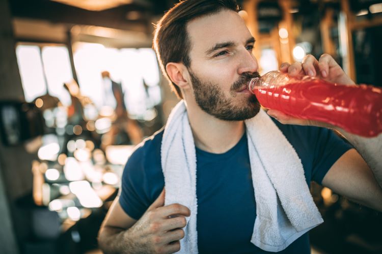 Man in a gym drinking a sports drink