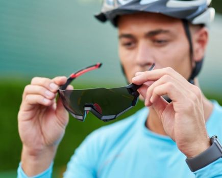 Males cyclist putting on sunglasses